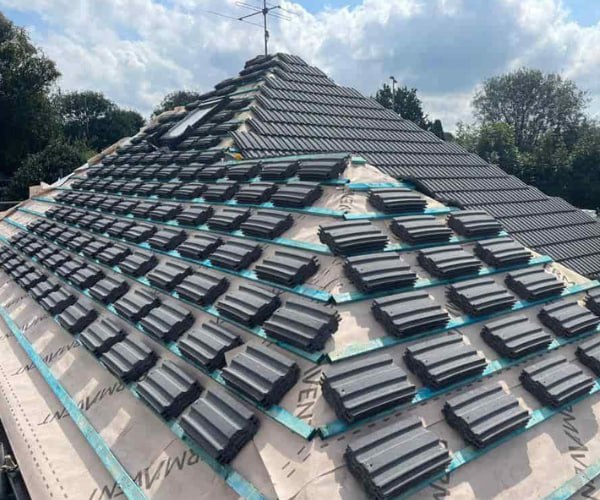 This is a photo of a new hip roof being installed. New felt, battens, and grey tiles have been installed, also a new velux window. Works carried out by KAM Roofing Askern